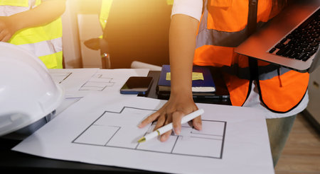 Closeup of team of industrial engineers meeting analyze machinery blueprints consult project on table in manufacturing factory. Working in manufacturing plant or production plant.の写真素材
