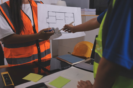 Closeup of team of industrial engineers meeting analyze machinery blueprints consult project on table in manufacturing factory. Working in manufacturing plant or production plant.の写真素材