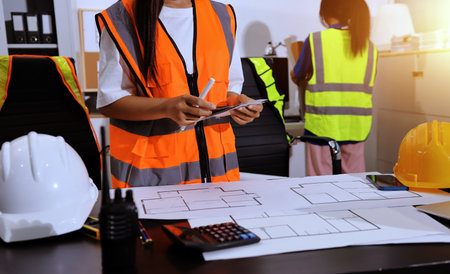 Closeup of team of industrial engineers meeting analyze machinery blueprints consult project on table in manufacturing factory. Working in manufacturing plant or production plant.の写真素材