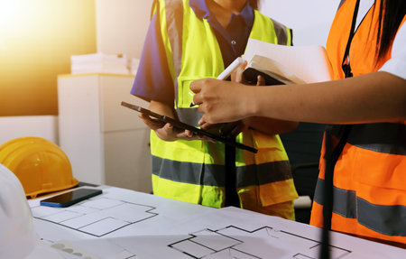Closeup of team of industrial engineers meeting analyze machinery blueprints consult project on table in manufacturing factory. Working in manufacturing plant or production plant.の写真素材