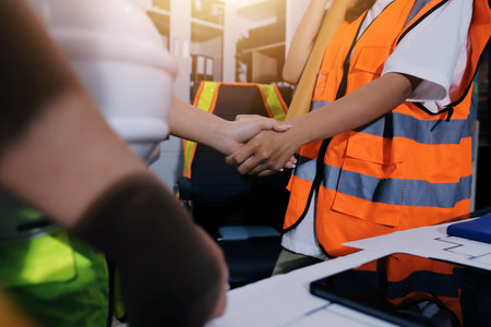 Closeup of team of industrial engineers meeting analyze machinery blueprints consult project on table in manufacturing factory. Working in manufacturing plant or production plant.の写真素材