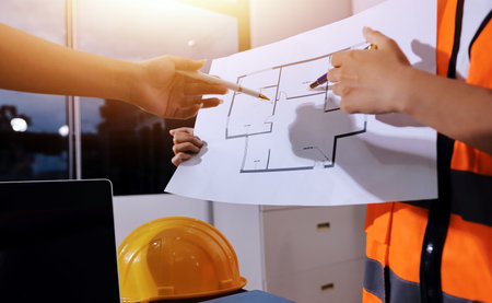 Closeup of team of industrial engineers meeting analyze machinery blueprints consult project on table in manufacturing factory. Working in manufacturing plant or production plant.の写真素材
