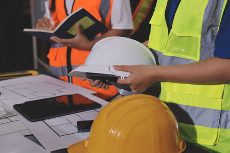 Closeup of team of industrial engineers meeting analyze machinery blueprints consult project on table in manufacturing factory. Working in manufacturing plant or production plant.の写真素材