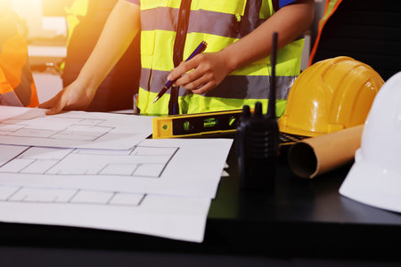 Closeup of team of industrial engineers meeting analyze machinery blueprints consult project on table in manufacturing factory. Working in manufacturing plant or production plant.の写真素材