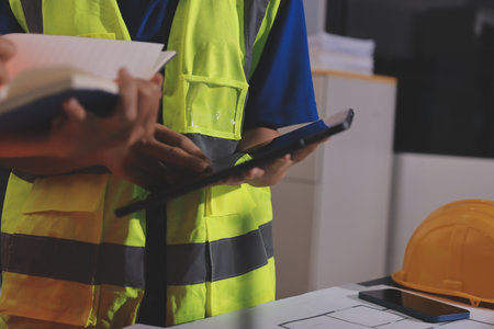 Closeup of team of industrial engineers meeting analyze machinery blueprints consult project on table in manufacturing factory. Working in manufacturing plant or production plant.の写真素材