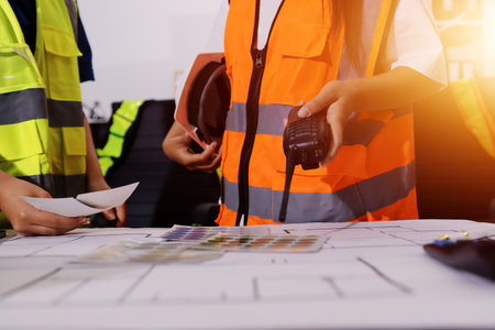 Closeup of team of industrial engineers meeting analyze machinery blueprints consult project on table in manufacturing factory. Working in manufacturing plant or production plant.の写真素材