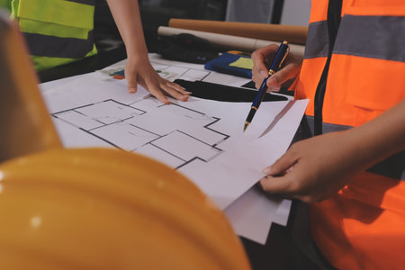 Closeup of team of industrial engineers meeting analyze machinery blueprints consult project on table in manufacturing factory. Working in manufacturing plant or production plant.の写真素材