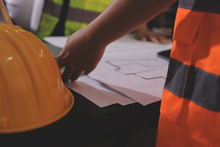 Closeup of team of industrial engineers meeting analyze machinery blueprints consult project on table in manufacturing factory. Working in manufacturing plant or production plant.の写真素材