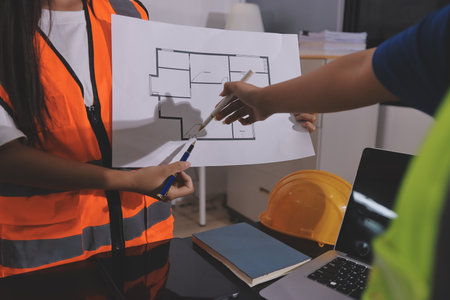 Closeup of team of industrial engineers meeting analyze machinery blueprints consult project on table in manufacturing factory. Working in manufacturing plant or production plant.の写真素材