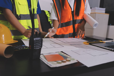 Closeup of team of industrial engineers meeting analyze machinery blueprints consult project on table in manufacturing factory. Working in manufacturing plant or production plant.の写真素材