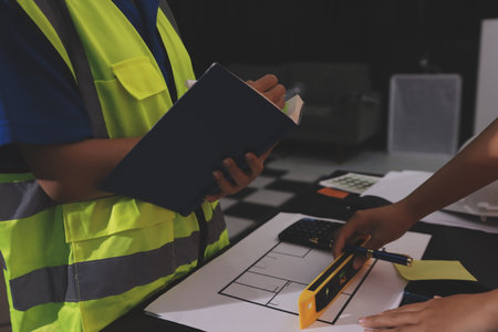 Closeup of team of industrial engineers meeting analyze machinery blueprints consult project on table in manufacturing factory. Working in manufacturing plant or production plant.の写真素材