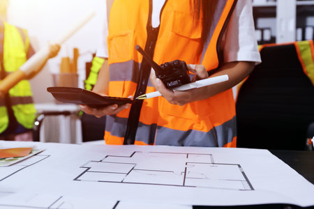 Closeup of team of industrial engineers meeting analyze machinery blueprints consult project on...