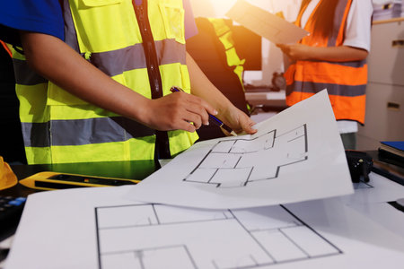 Closeup of team of industrial engineers meeting analyze machinery blueprints consult project on...