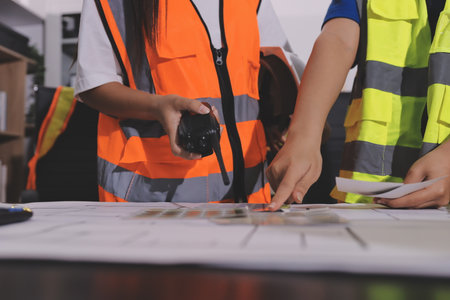 Closeup of team of industrial engineers meeting analyze machinery blueprints consult project on table in manufacturing factory. Working in manufacturing plant or production plant.の写真素材