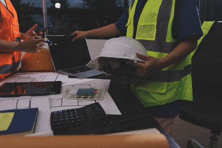 Closeup of team of industrial engineers meeting analyze machinery blueprints consult project on table in manufacturing factory. Working in manufacturing plant or production plant.の写真素材