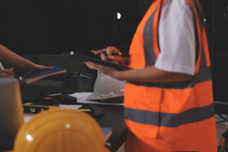 Closeup of team of industrial engineers meeting analyze machinery blueprints consult project on table in manufacturing factory. Working in manufacturing plant or production plant.の写真素材