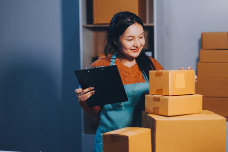 Startup SME small business entrepreneur of freelance Asian woman wearing apron using laptop and box...