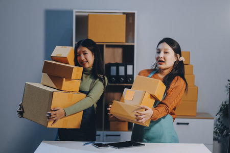 Startup SME small business entrepreneur of freelance Asian woman wearing apron using laptop and box to receive and review orders online to prepare to pack sell to customers, online sme business ideas.の写真素材