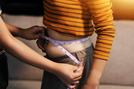 Cropped shot of woman touching and squeezing her fat belly.の写真素材