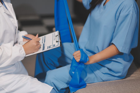 Physical therapist assisting a patient while giving exercising treatment on stretching her arm with...