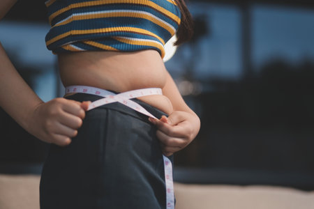 Cropped shot of woman touching and squeezing her fat belly.の写真素材