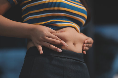 Cropped shot of woman touching and squeezing her fat belly.の写真素材