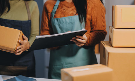 Startup SME small business entrepreneur of freelance Asian woman wearing apron using laptop and box...