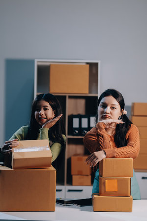 Startup SME small business entrepreneur of freelance Asian woman wearing apron using laptop and box to receive and review orders online to prepare to pack sell to customers, online sme business ideas.の写真素材