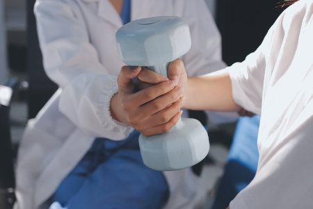 Unrecognizable uses blue hand weight during physical therapy sessionの写真素材