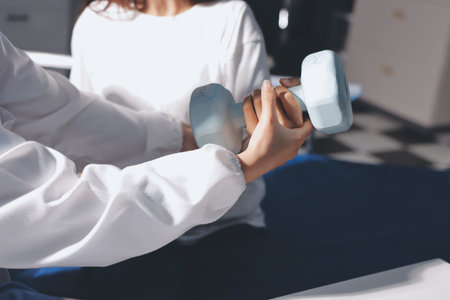 Unrecognizable uses blue hand weight during physical therapy session
