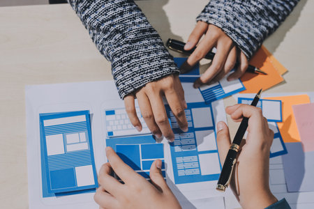 Group of young application developers analyzing uxui mobile app templates during a working meetingの写真素材