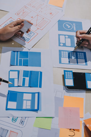 Group of young application developers analyzing uxui mobile app templates during a working meetingの写真素材