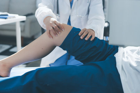 Female doctor hands doing physical therapy By extending the leg and knee of a male patientの写真素材