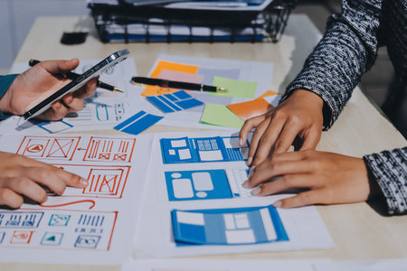 Group of young application developers analyzing uxui mobile app templates during a working meeting