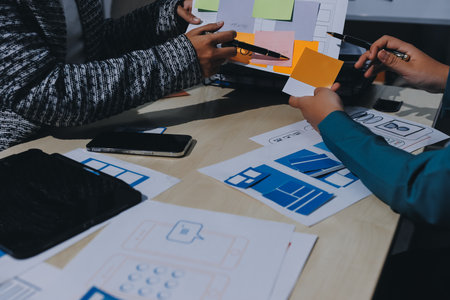 Group of young application developers analyzing uxui mobile app templates during a working meeting