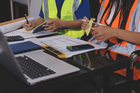 Closeup of team of industrial engineers meeting analyze machinery blueprints consult project on table in manufacturing factory. Working in manufacturing plant or production plant.の写真素材