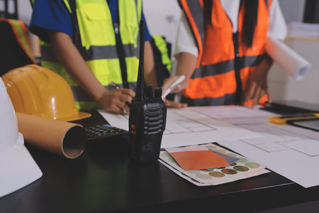 Closeup of team of industrial engineers meeting analyze machinery blueprints consult project on table in manufacturing factory. Working in manufacturing plant or production plant.の写真素材