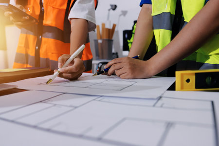 Closeup of team of industrial engineers meeting analyze machinery blueprints consult project on table in manufacturing factory. Working in manufacturing plant or production plant.の写真素材