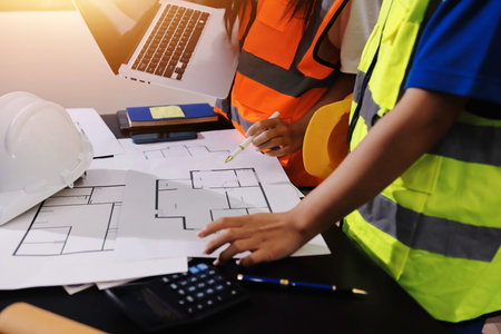 Closeup of team of industrial engineers meeting analyze machinery blueprints consult project on table in manufacturing factory. Working in manufacturing plant or production plant.の写真素材