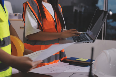 Closeup of team of industrial engineers meeting analyze machinery blueprints consult project on table in manufacturing factory. Working in manufacturing plant or production plant.の写真素材