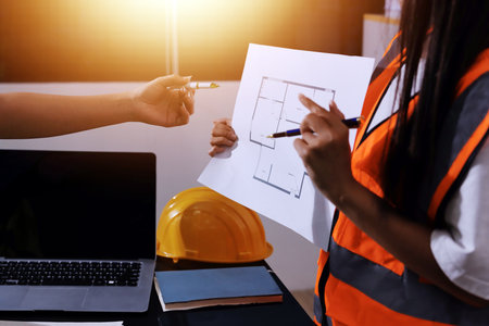 Closeup of team of industrial engineers meeting analyze machinery blueprints consult project on table in manufacturing factory. Working in manufacturing plant or production plant.の写真素材