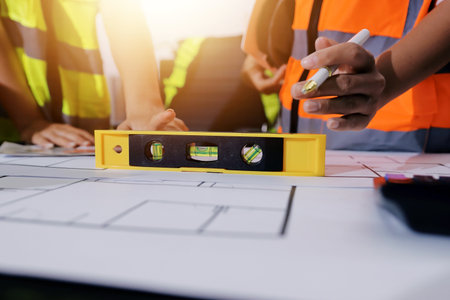 Closeup of team of industrial engineers meeting analyze machinery blueprints consult project on table in manufacturing factory. Working in manufacturing plant or production plant.の写真素材