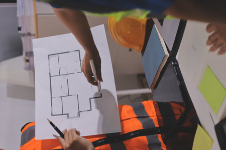 Closeup of team of industrial engineers meeting analyze machinery blueprints consult project on table in manufacturing factory. Working in manufacturing plant or production plant.の写真素材