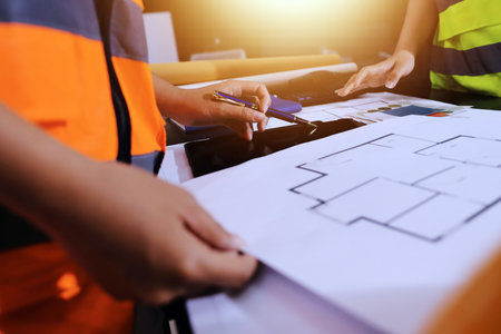 Closeup of team of industrial engineers meeting analyze machinery blueprints consult project on...