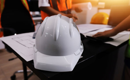 Closeup of team of industrial engineers meeting analyze machinery blueprints consult project on table in manufacturing factory. Working in manufacturing plant or production plant.の写真素材