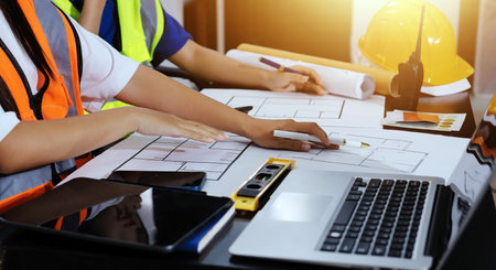 Closeup of team of industrial engineers meeting analyze machinery blueprints consult project on table in manufacturing factory. Working in manufacturing plant or production plant.の写真素材