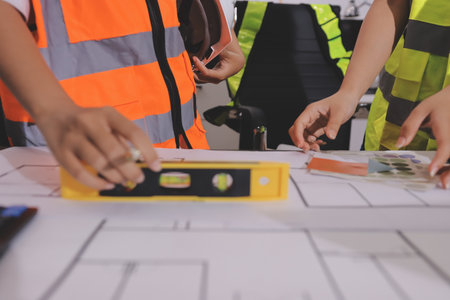 Closeup of team of industrial engineers meeting analyze machinery blueprints consult project on...