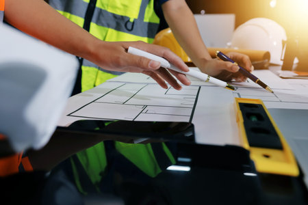 Closeup of team of industrial engineers meeting analyze machinery blueprints consult project on table in manufacturing factory. Working in manufacturing plant or production plant.の写真素材
