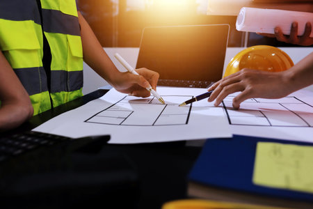 Closeup of team of industrial engineers meeting analyze machinery blueprints consult project on table in manufacturing factory. Working in manufacturing plant or production plant.の写真素材