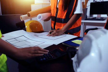 Closeup of team of industrial engineers meeting analyze machinery blueprints consult project on table in manufacturing factory. Working in manufacturing plant or production plant.の写真素材